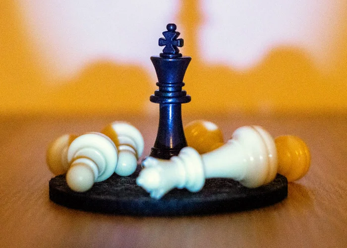 Schwarzer König beim Schach im Zentrum umgefallener weißer Schachfiguren
